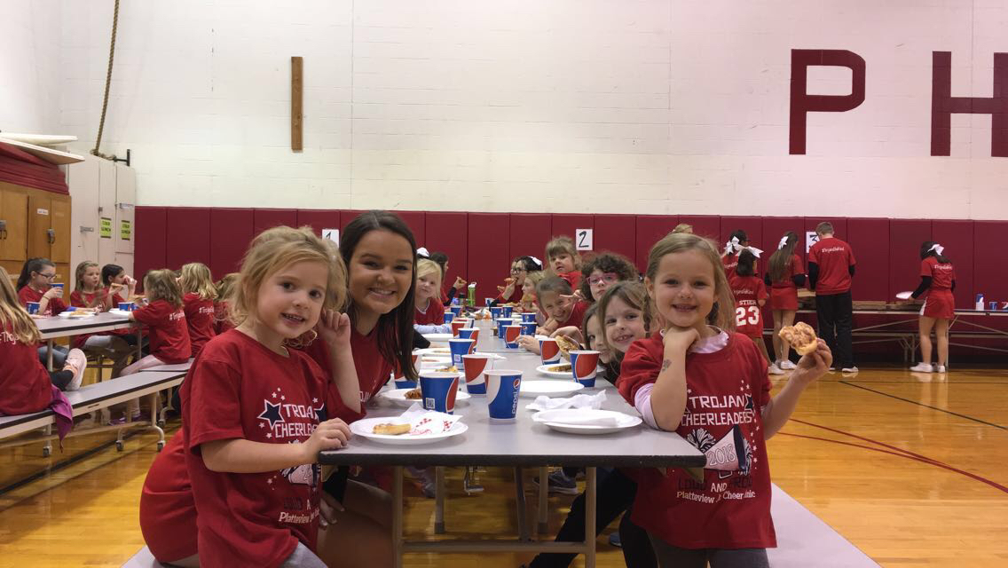 Senior co-captain Shelby Lagana and the younger kids from the Jr. Cheer Clinic practice their smiles and being enthusiastic before the game.