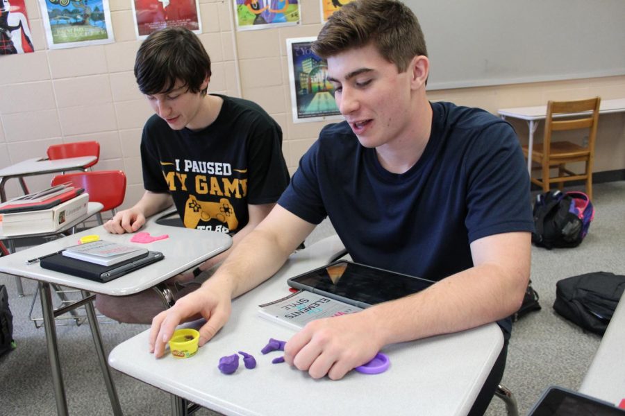 Seniors Joseph Brinkman and Nicholas Eurich build a representation of themselves out of play-dough on the first day of fourth period English.