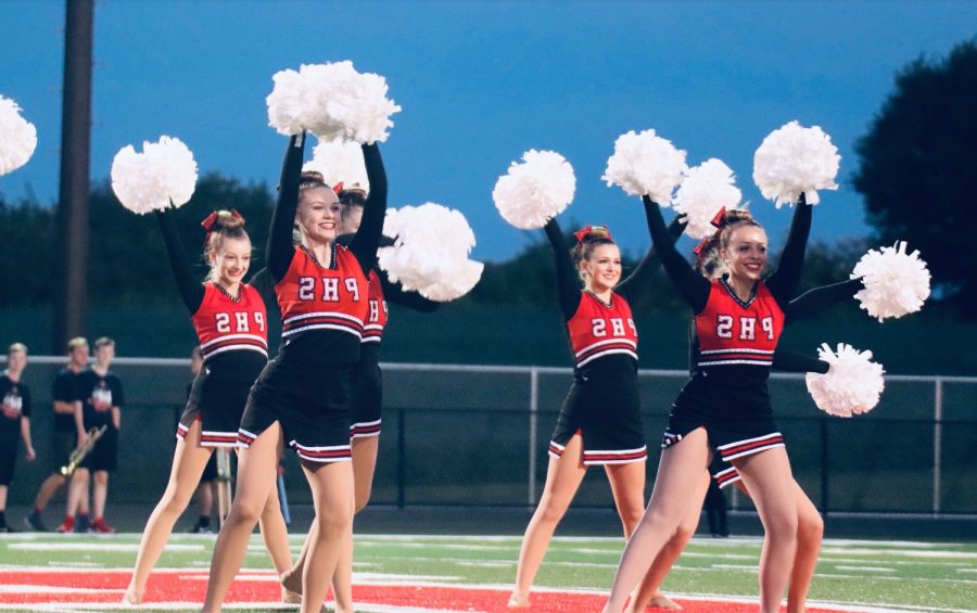 Striking a pose with their heads and  pom-poms held high, Emma Pitman (11), Lauren Jones (12), Torey Swanson (11), and Brooke Williams (9) perform at a football game.