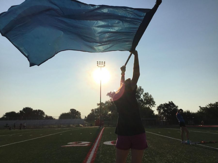 Color Guard practices outside in the air, waving the Trojan colors in the sun.
